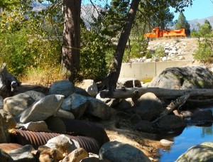 A cement filled culvert, foreground, is near the river. And vehicles on Highway 50 roar by the property.